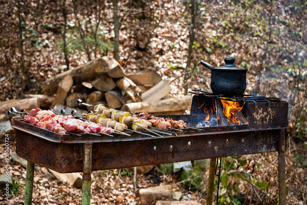 Grilled kebab cooking on metal skewer with potatoes.. Roasted meat cooked at barbecue. Grill, picnic, street food. Grilled kebab cooking on metal skewer with potatoes.. Roasted meat cooked at barbecue. Grill, picnic, street food.
