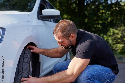 Fotografija Man examining tires at his new car