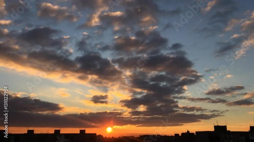 Time lapse of clouds during the sunset. Evening clouds float over the city rooftops