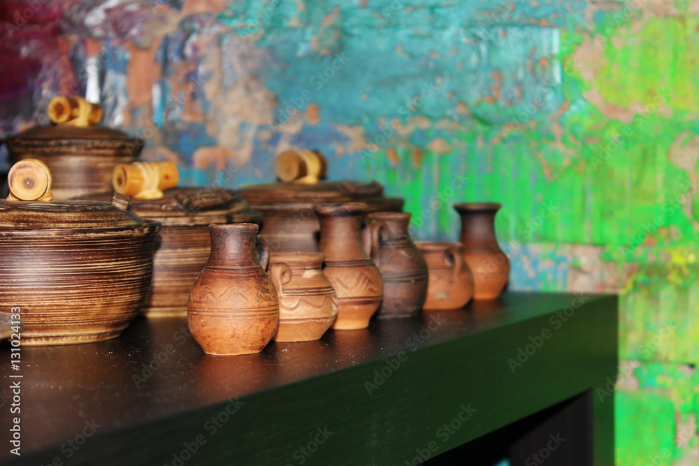 many small clay jugs and pots standing on a green table. many small clay jugs and pots standing on a green table.