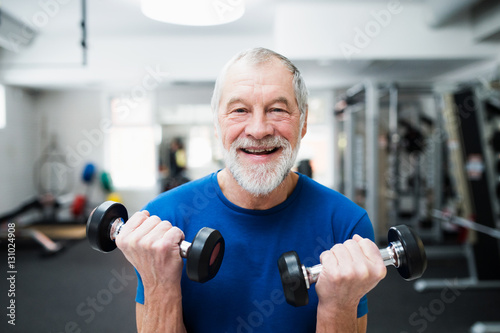 Senior man in gym working out with weights.
