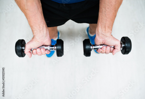Hands of senior man in gym working out with weights