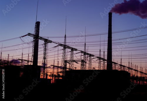 distribution electric substation with power lines and transformers, at sunset.