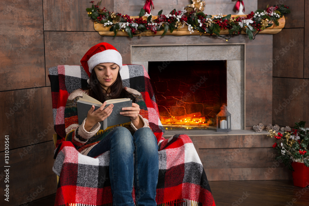 Attractive concentrated woman in funny Christmas hat reading whi
