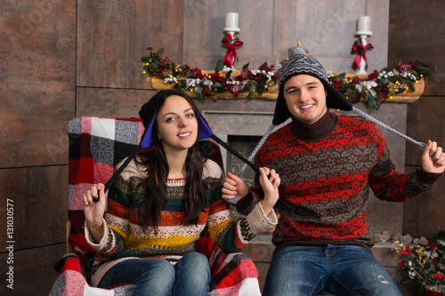 Attractive smiling couple in funny knitted Nordic hats sitting i