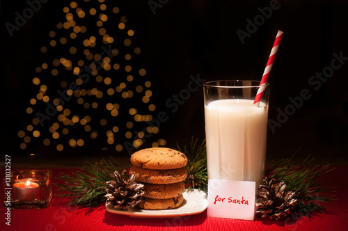 Christmas cookies milk note for Santa in front of lights new year tree