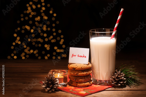 Christmas cookies milk note for Santa in front of lights new year tree