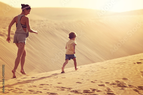 Mother with son running in a desert in Gran Canaria