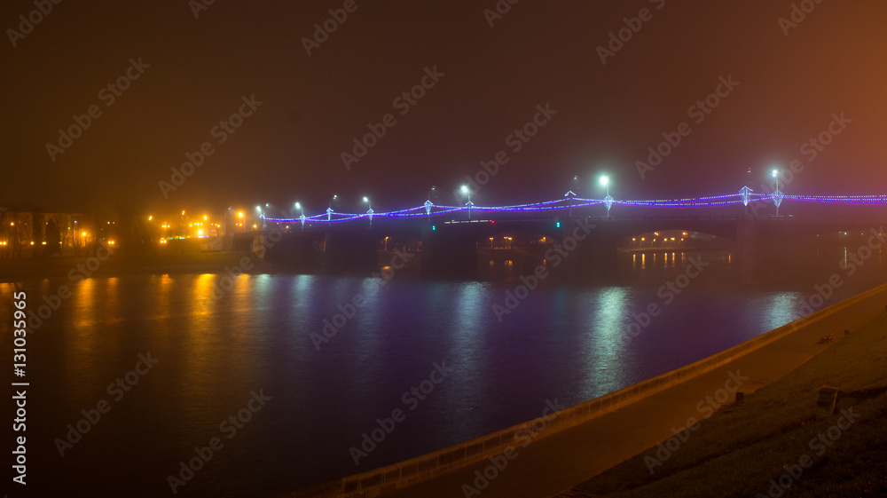 Novovolzhsky bridge over the Volga River in the fog and with night lighting. Built in 1956.