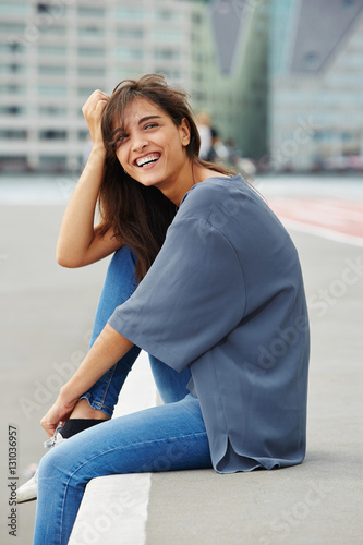 attractive young woman sitting outdoors and laughing
