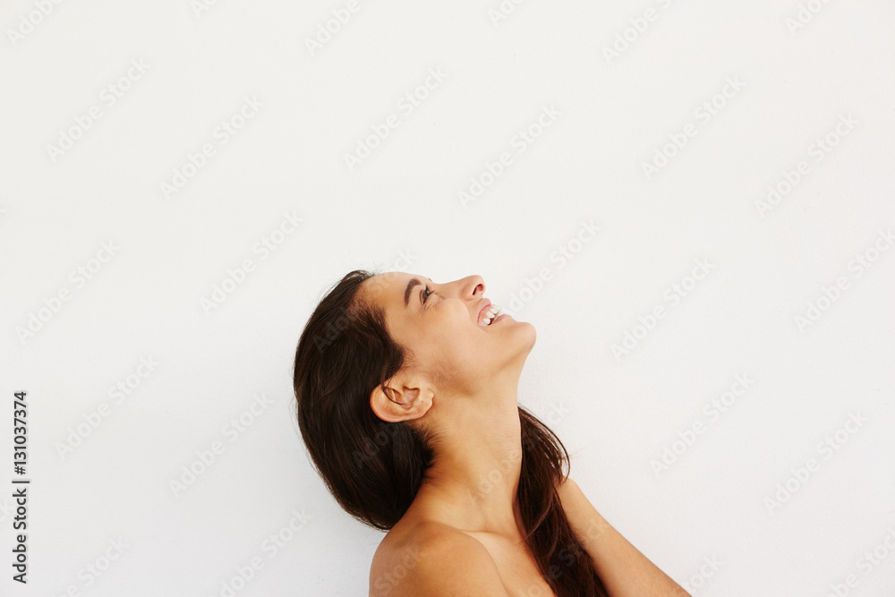 young female smiling against while wall and looking up young female smiling against while wall and looking up