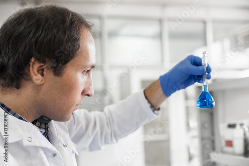 Male laboratory researcher performs tests with blue liquid