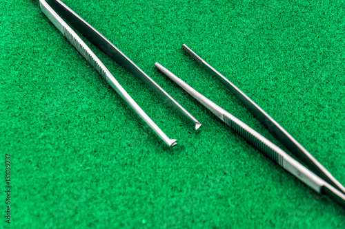 Two types of surgical tweezers isolated on green background