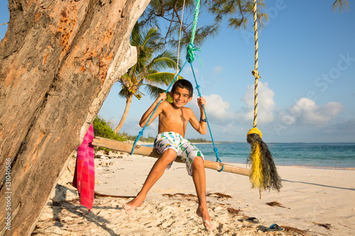 Portrait of smiling boy sitting on a swing at beach