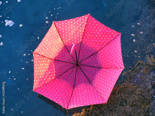 Red upturned umbrella floating on water surface
