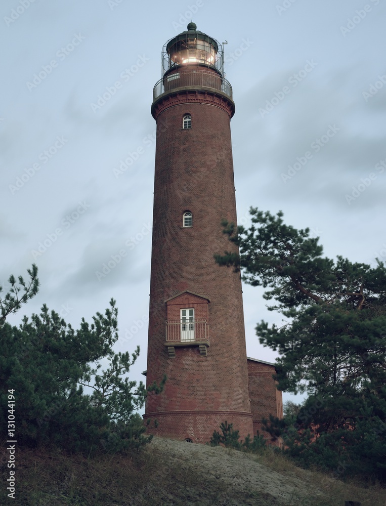 Historical lighthouse. Shinning lighthouse,  dunes and pine tree. Tower illuminated