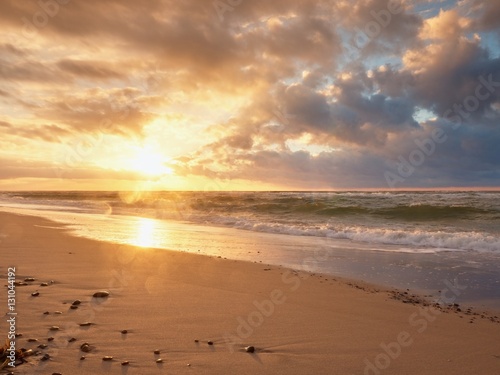 Beach sand with stones and water trails. Traces on beach at smooth sea 