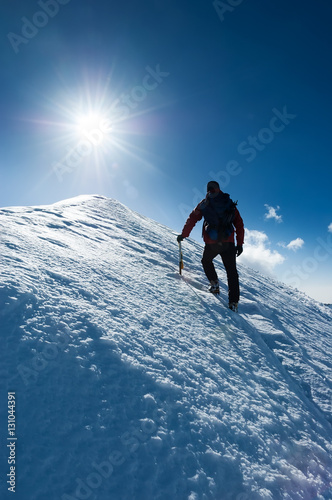 Mountaineer reaches the summit of a snowy peak. Concept: courage, perseverance, strength. Swiss Alps, Zermatt, Europe.