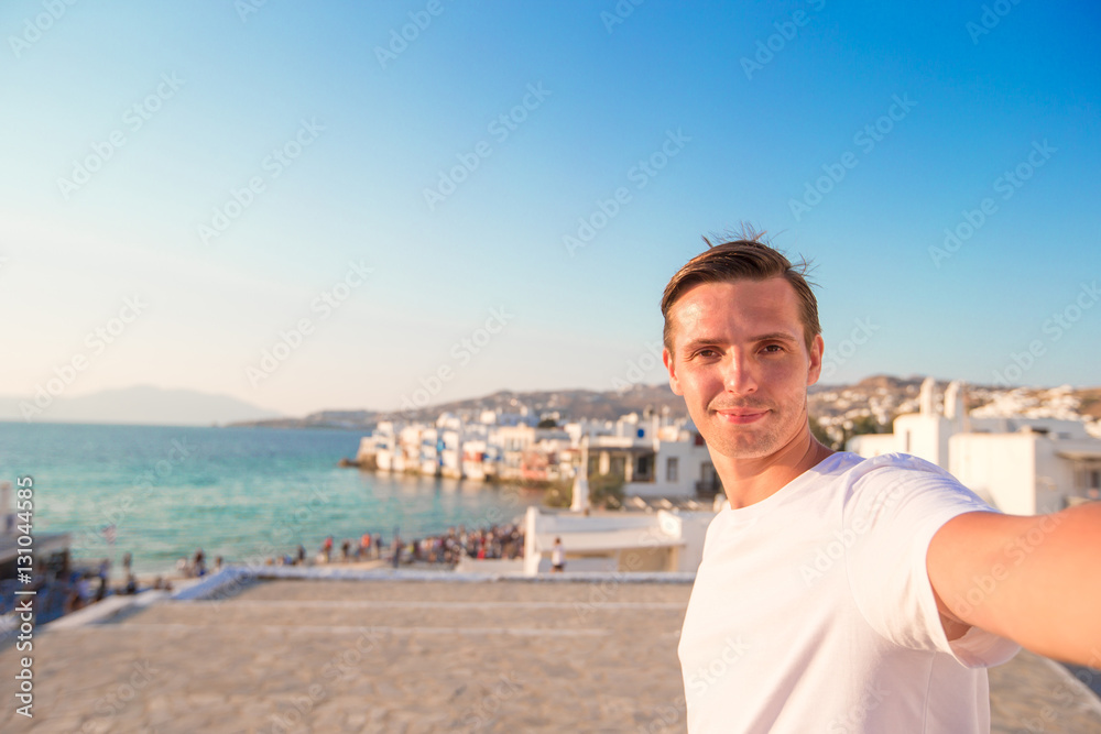 Young man taking selfie portrait background Little Venice in Mykonos