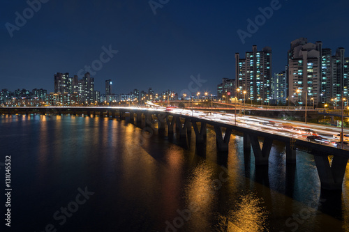 Lit residential district along the Han River and traffic on a bridge in Seoul  South Korea  at night.
