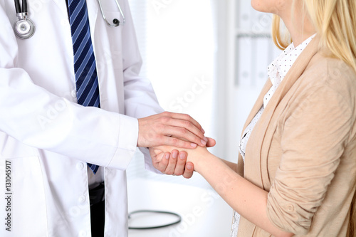 Hand of doctor reassuring her female patient. Medical ethics and trust concept