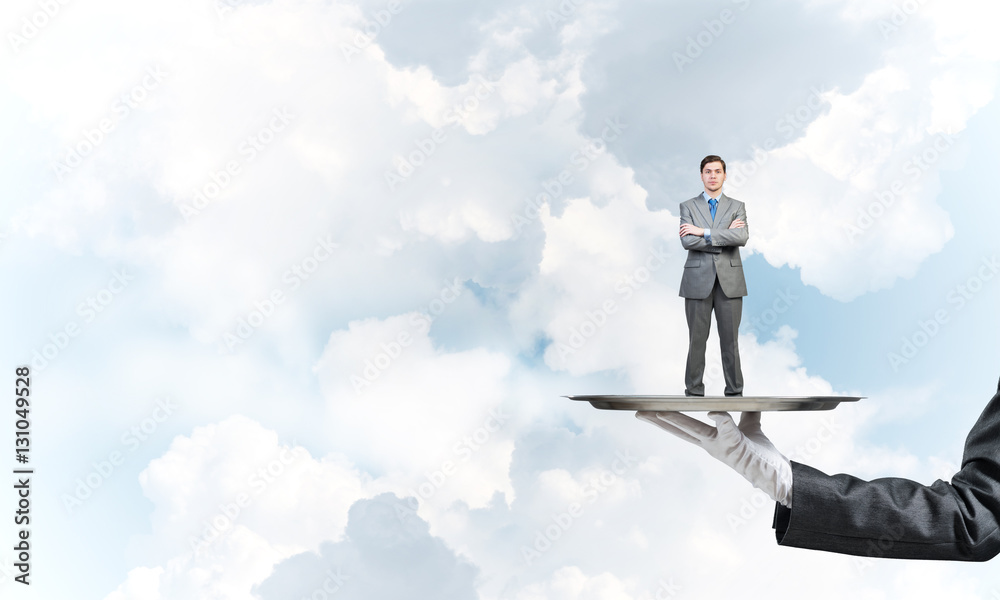 Confident businessman presented on metal tray against blue sky background Confident businessman presented on metal tray against blue sky background
