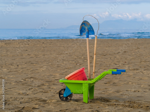 Fototapeta Naklejka Na Ścianę i Meble -  toys on the beach plastic wheelbarrow, bucket and spade