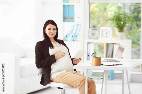 Young pregnant woman holdin...