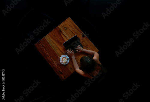 chica en cafeteria con luz muy tenue y fondo oscuro photo