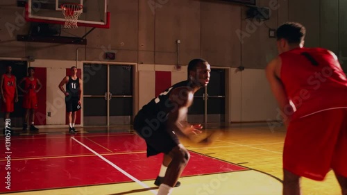 Two basketball players playing one on one while their teammates stand behind the lines