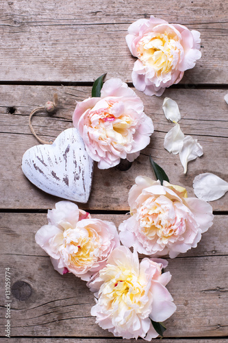 Decorative heart and  pink peonies flowers on aged wooden backgr