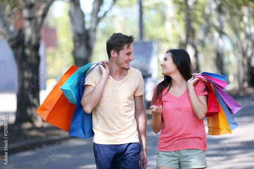 Happy couple carrying colorful bags outdoors