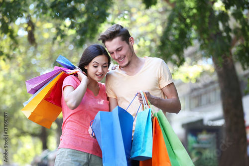 Happy couple with colorful shopping bags in park