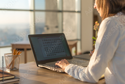 Female writer typing using laptop keyboard at her workplace in the morning. Woman writing blogs online, side view close-up picture.