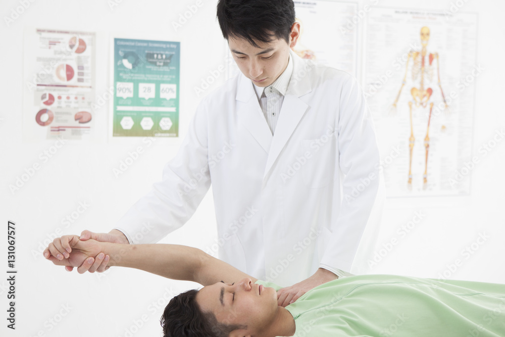 The doctor is examining the male's shoulder joint