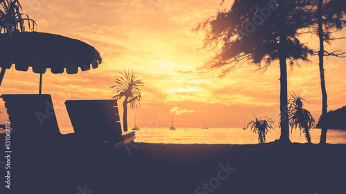 Silhouette chair and umbrella on topical sunset beach with sailboat.