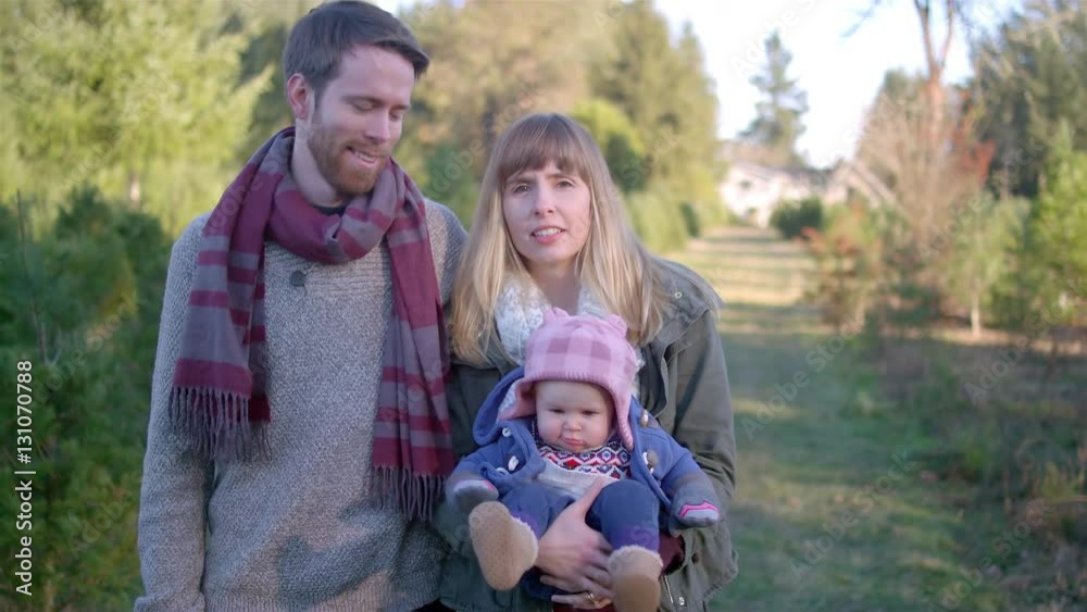 Portrait of a young mother, father and their baby girl at a Christmas tree farm Portrait of a young mother, father and their baby girl at a Christmas tree farm