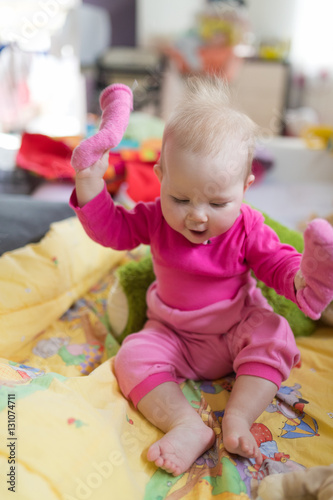 Cute bare feet baby girl showing her pink socks.