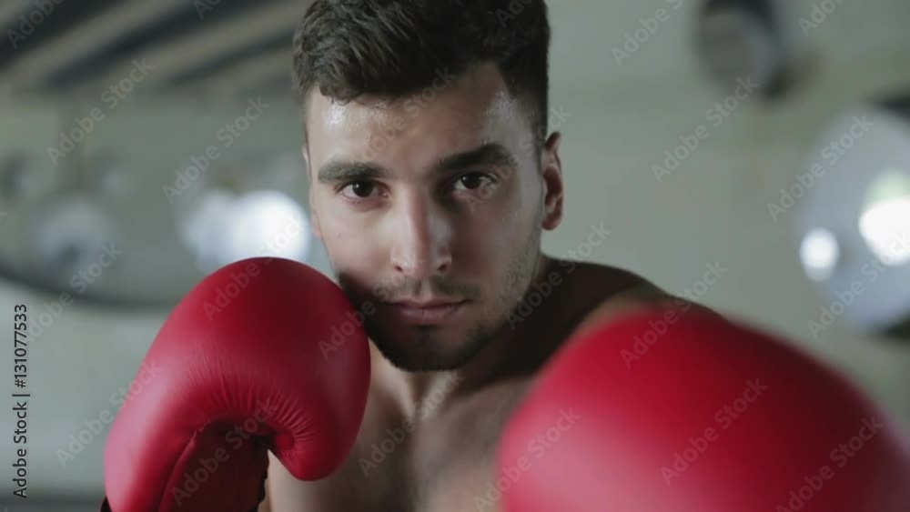 Slow motion. Young boxer with a confident eyes is waiting the fight ...