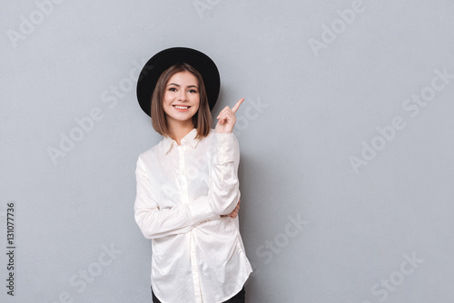 Woman in hat pointing finger away and looking at camera