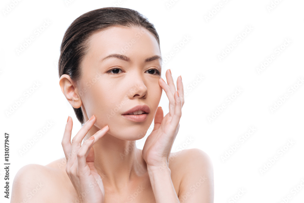 Positive beautiful Chinese woman applying a cream on her face Positive beautiful Chinese woman applying a cream on her face