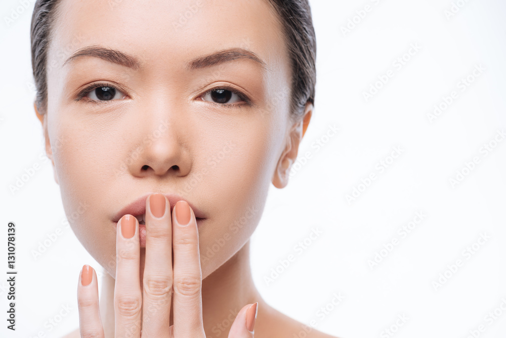 Shy young Korean woman touching her lips in the studio Shy young Korean woman touching her lips in the studio