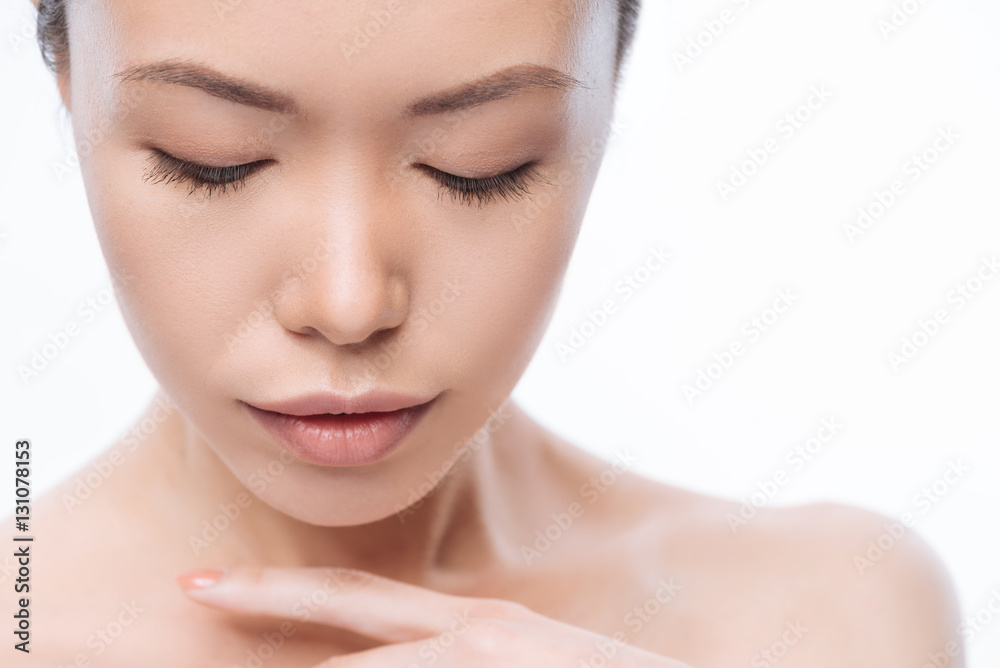 Gentle young Korean woman touching her skin in the studio Gentle young Korean woman touching her skin in the studio
