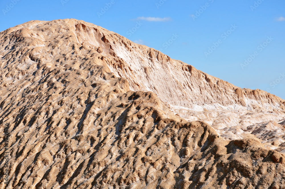 A pile of sand with salt from the sandy industrial career against the blue sky. A pile of sand with salt from the sandy industrial career against the blue sky.