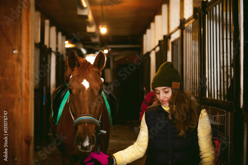 young woman rider engaged since a horse in the stables, prepare for departure © evgeniykleymenov