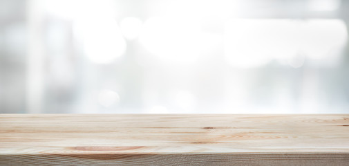.Wood table top on blur glass window wall building background.