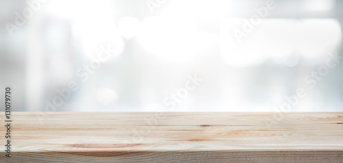 .Wood table top on blur glass window wall building background.