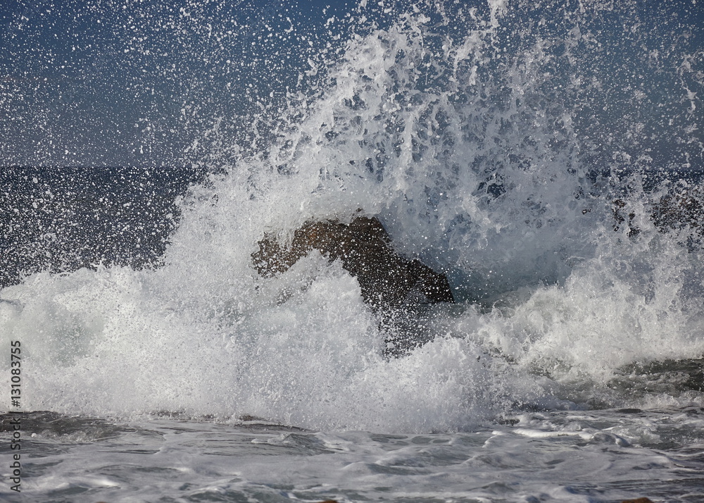 Obraz premium splits waves against rocks in the sea