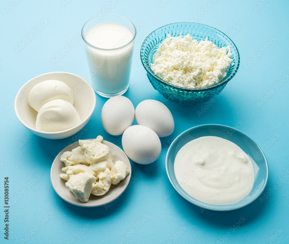 Protein products: cheese, cream, milk, eggs on the blue backgrou Protein products: cheese, cream, milk, eggs on the blue backgrou