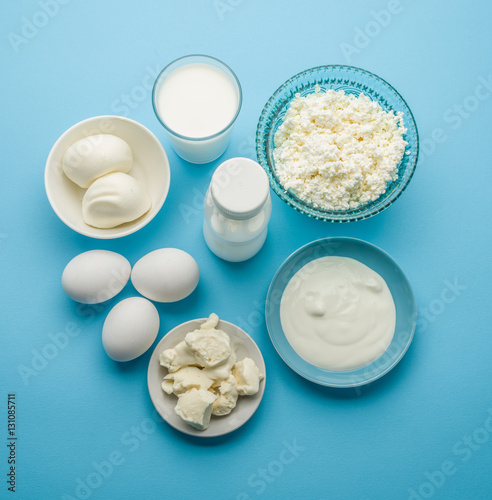 Protein products: cheese, cream, milk, eggs on the blue backgrou